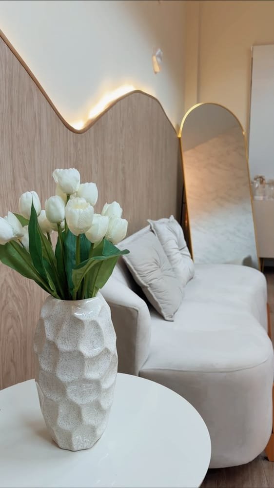 Detalhe da recepção: tulipas brancas, mesa lateral e espelho arqueado dourado